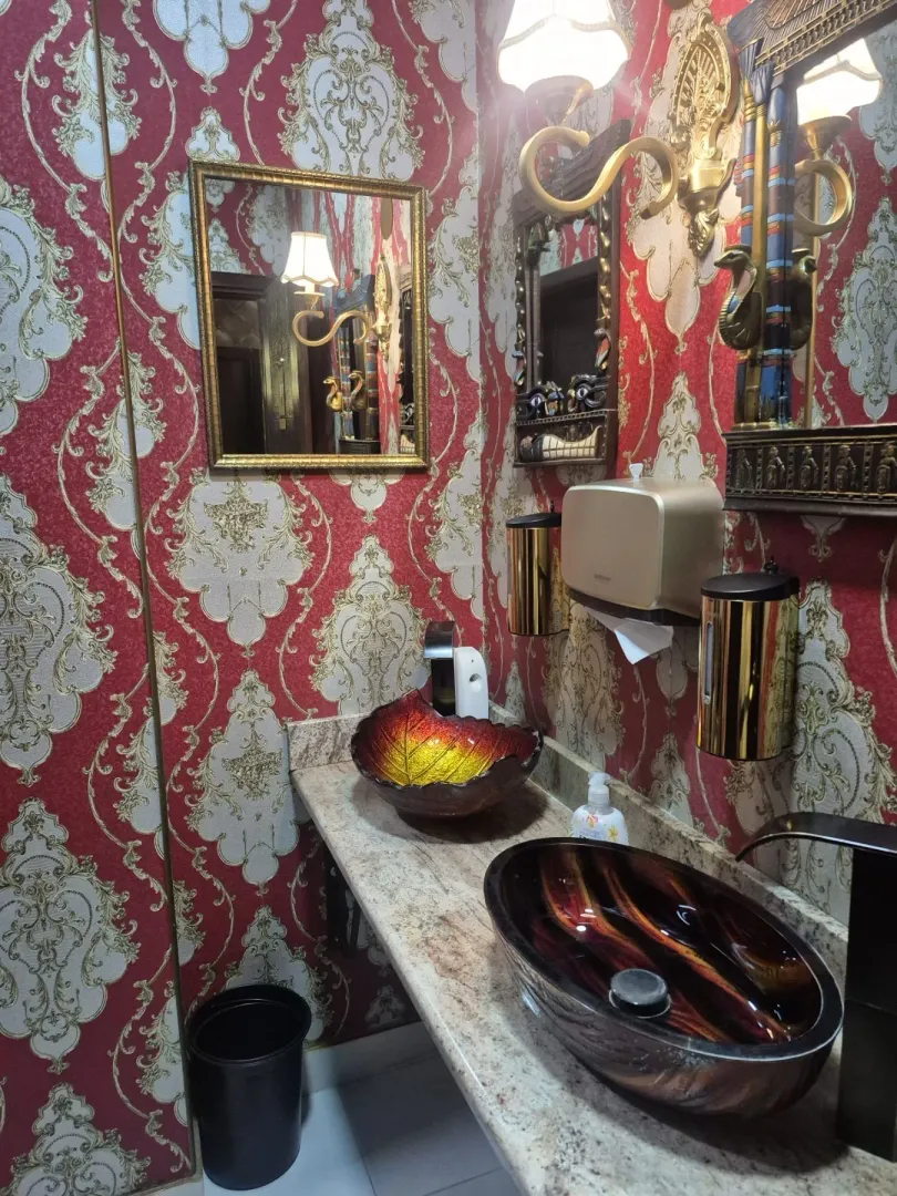 Bathroom with ornate wallpaper and two decorative sinks.