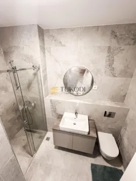 Modern bathroom lined with gray tiles, featuring a walk-in shower, washbasin, and toilet. - image 8