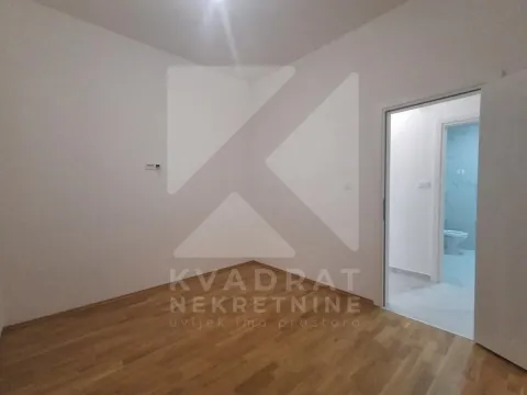 Prazna soba sa parketom i pogledom na kupatilo kroz vrata. - image 9