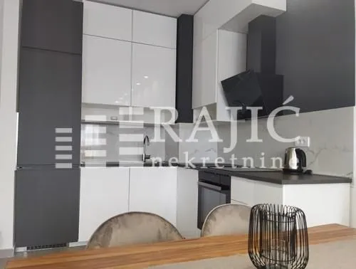 Modern kitchen with white and grey cabinets and built-in appliances.