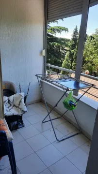 Balkon sa sušilicom za veš i pogledom na drveće. - image 6