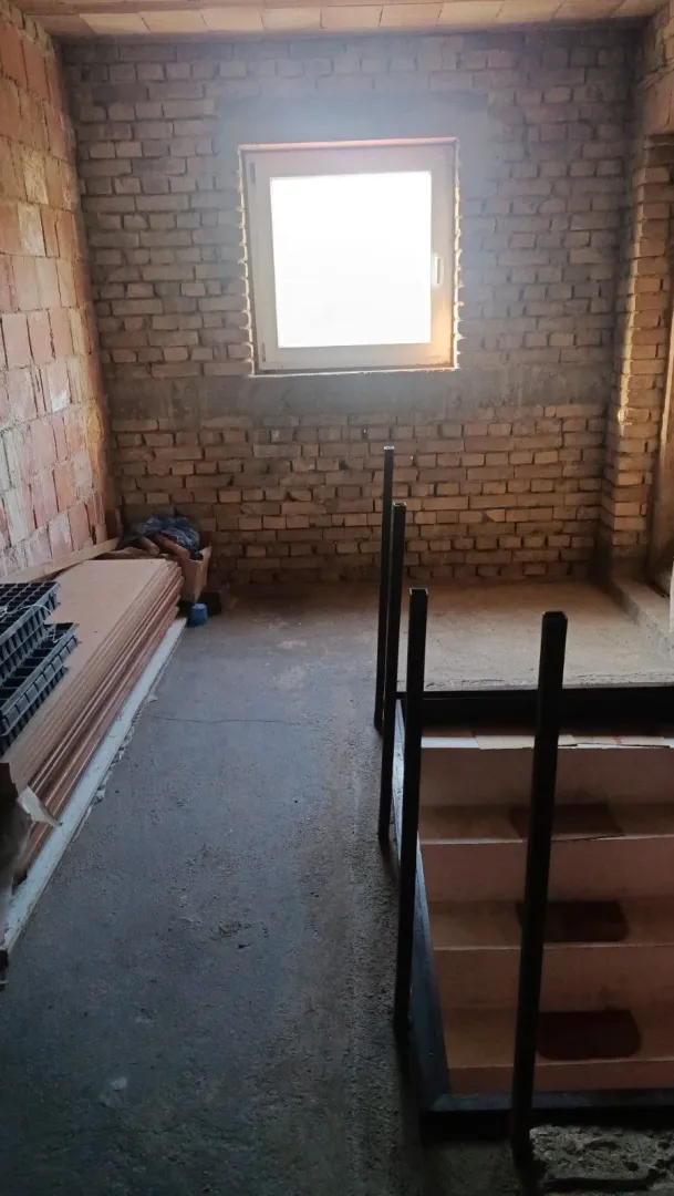 Pogled na stepenište u objektu u izgradnji sa ciglenim zidovima i prozorom.