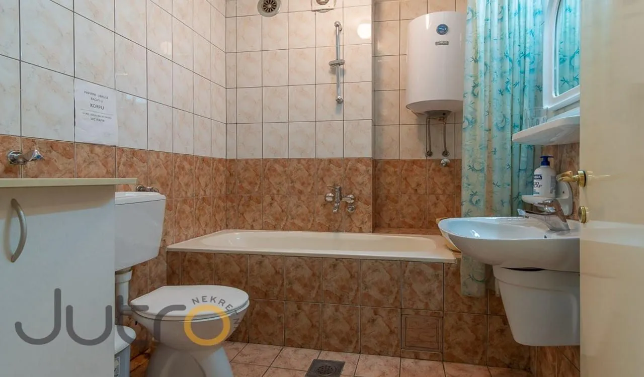 Bathroom equipped with a bathtub, washbasin, toilet, and water heater.