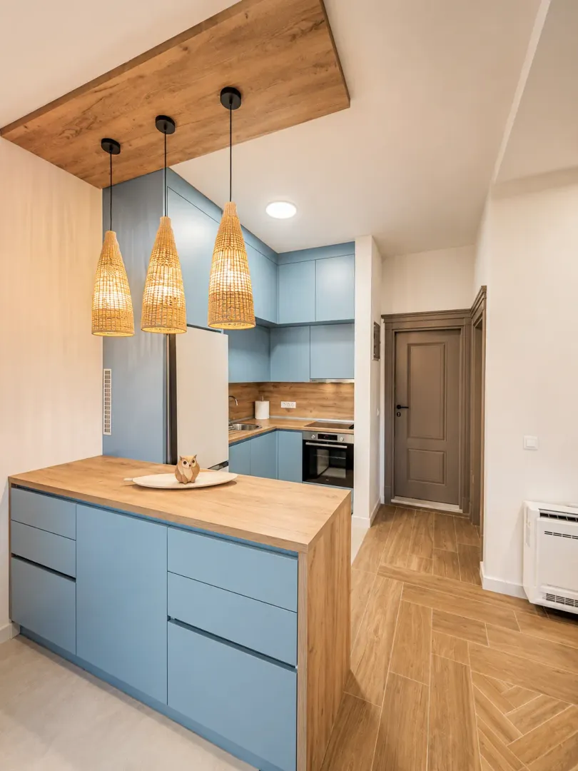 Modern kitchen with blue cabinets, wooden countertop and pendant lights.