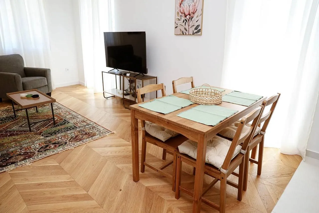 Dnevni boravak sa trpezarijskim stolom i TV-om.