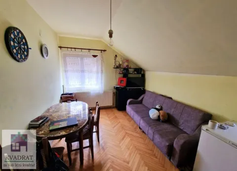 Living room with a sofa, dining table, and sloped ceiling. - image 2
