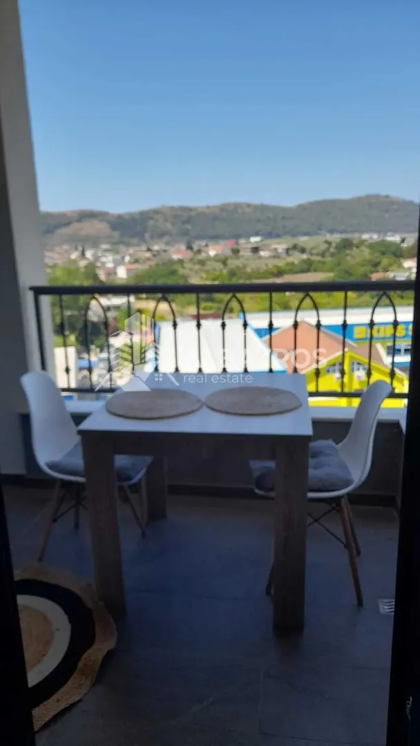 Natkriveni balkon sa trpezarijskim stolom i pogledom na prirodu i grad.