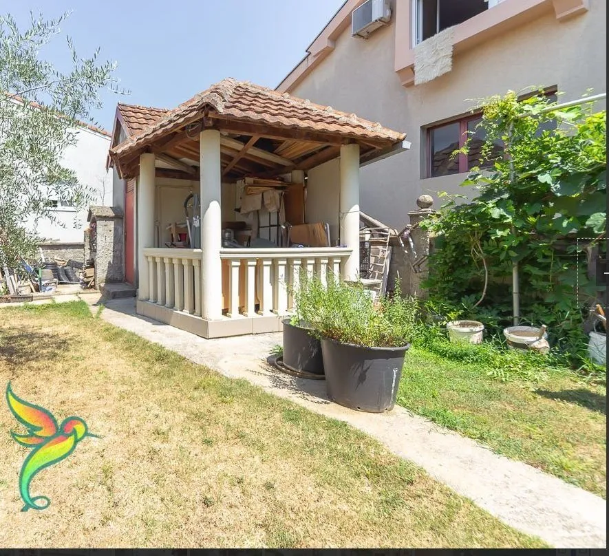 Dvorište sa natkrivenim ljetnjikovcem i zelenilom pored kuće.
