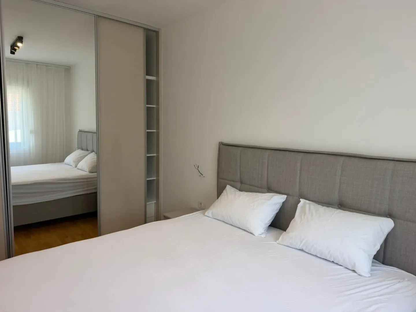Modern bedroom with a double bed and a large mirrored fitted wardrobe.