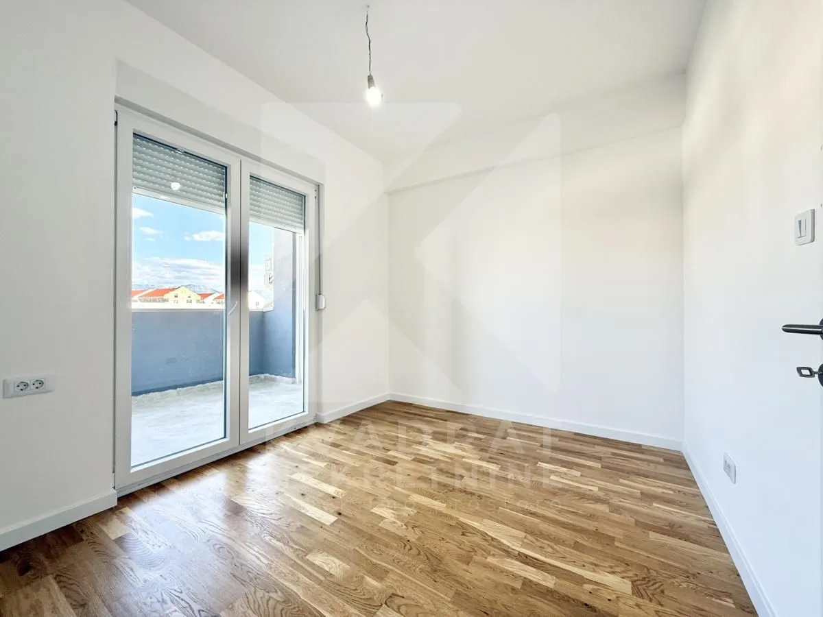 Empty room with wooden flooring and access to the terrace.