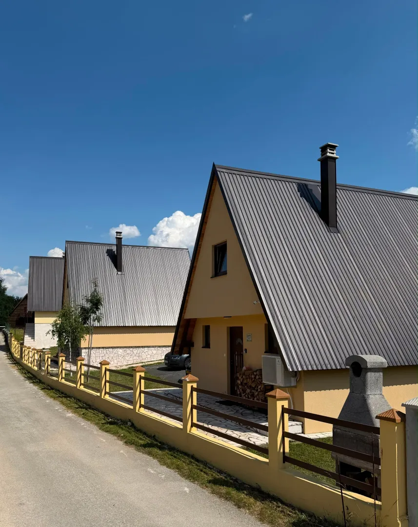 Spoljašnji izgled kuće sa dvorištem i ogradom pored puta.