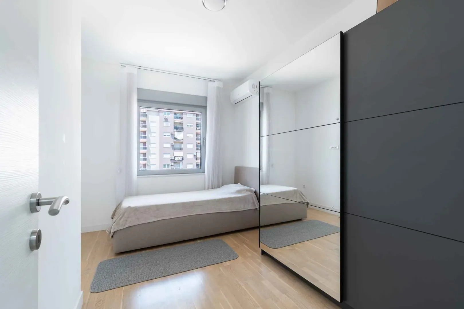 Bright bedroom with a bed and a large mirrored wardrobe.