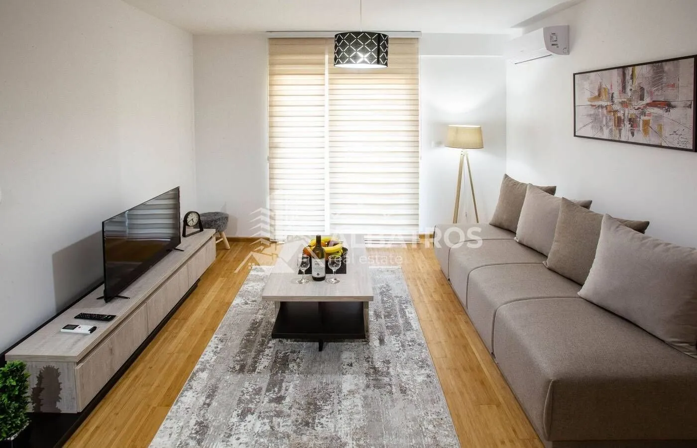 Living room with a sofa, TV, and coffee table in bright tones.
