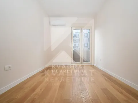 Empty room with wooden flooring, air conditioning unit, and balcony doors. - image 4