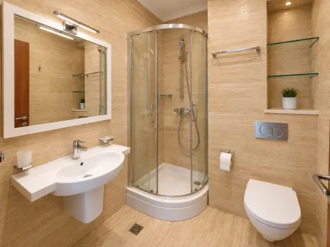 Kupatilo opremljeno umivaonikom, tuš kabinom i toaletom u bež tonovima. - image 10