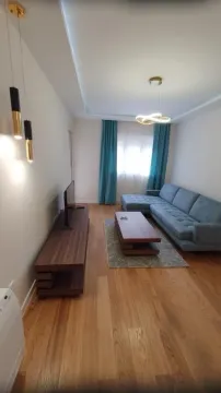 Modern living room with a sofa, TV unit, and wooden flooring. - image 2