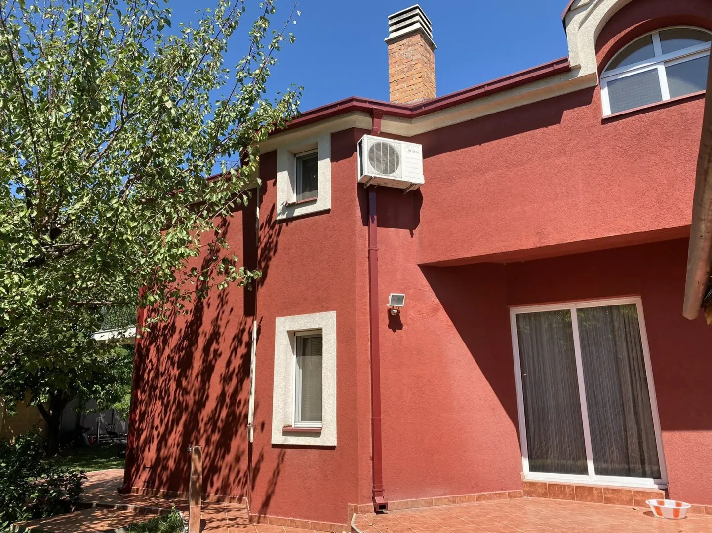 Exterior of a house with a red facade and a tiled yard.