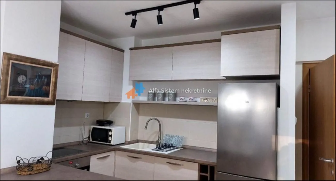 Small equipped kitchen with white cabinetry and a refrigerator.