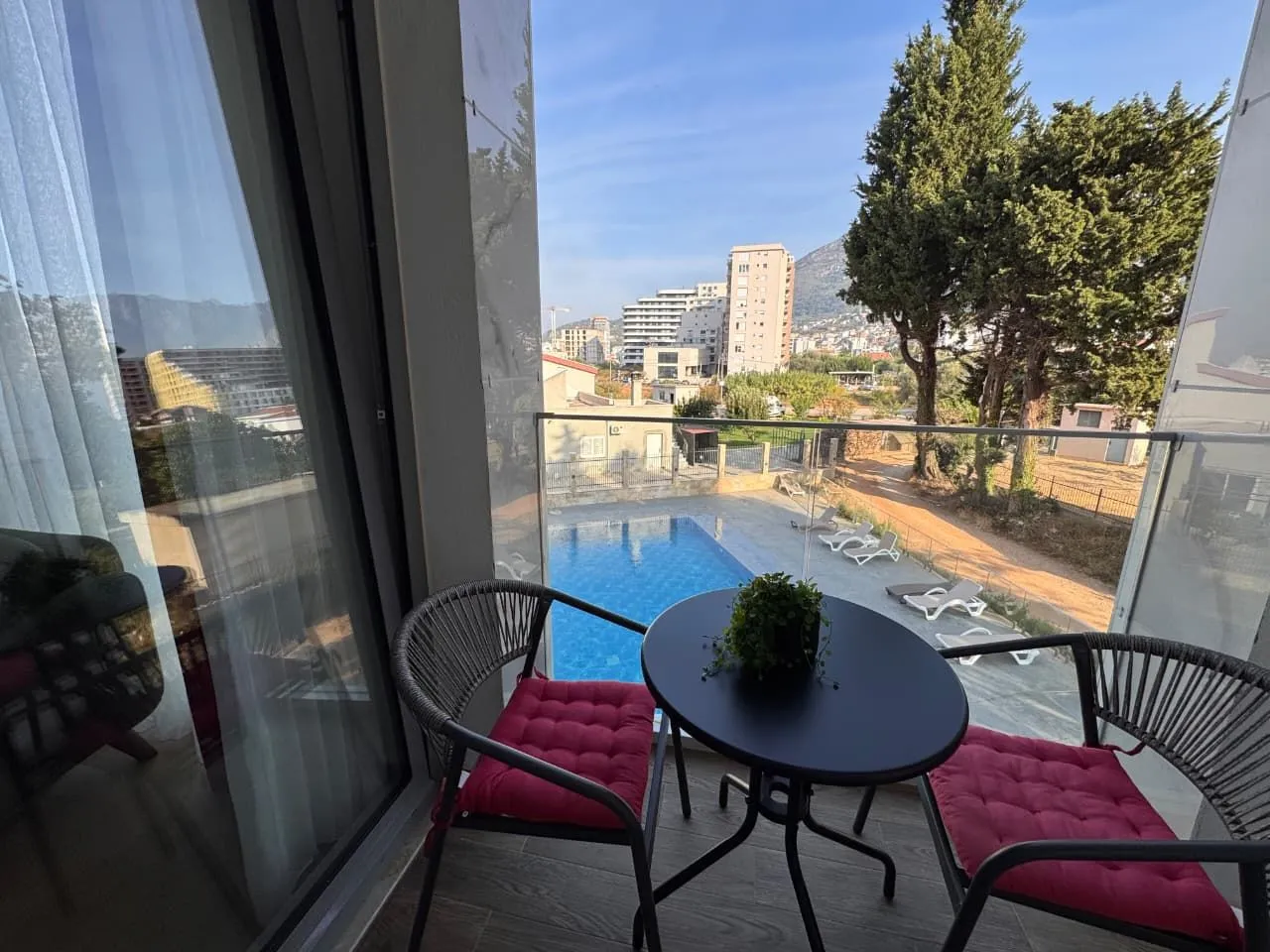 Namješten balkon sa stolom i stolicama i pogledom na bazen i okolinu.