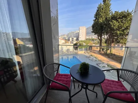 Namješten balkon sa stolom i stolicama i pogledom na bazen i okolinu. - image 15