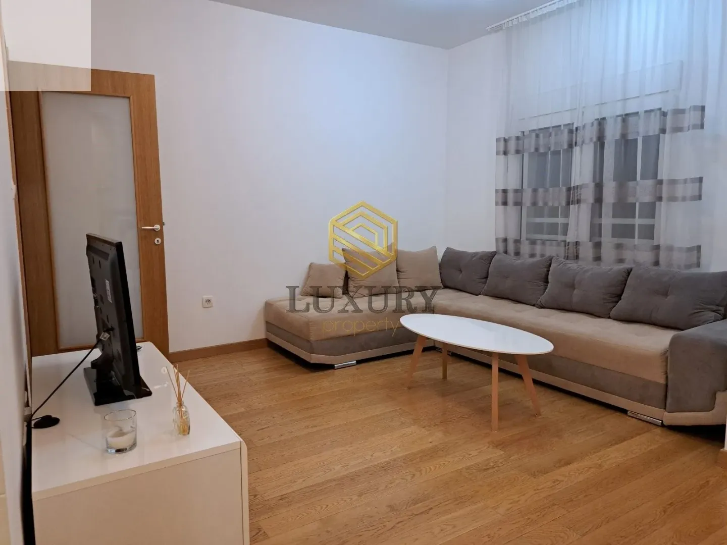 Dnevni boravak sa garniturom, stočićem i televizorom.