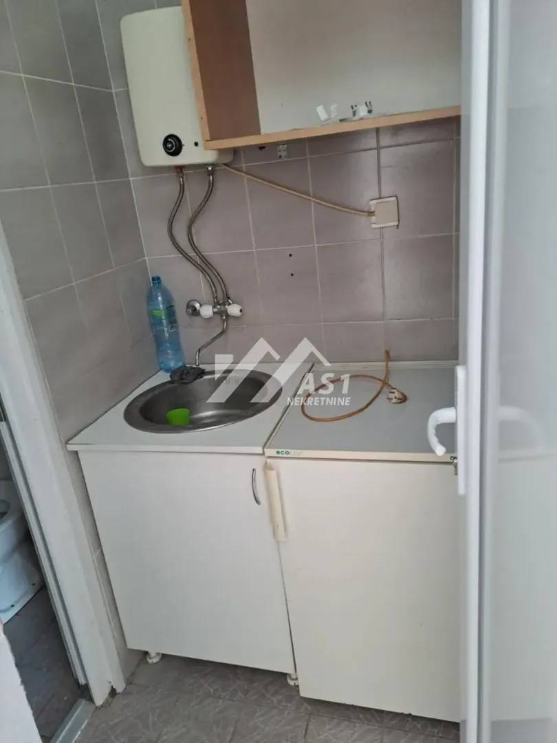 Small kitchen with a sink, base cabinets, and a water heater on the wall.