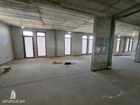View of an empty space under construction with concrete pillars and windows. - image 3