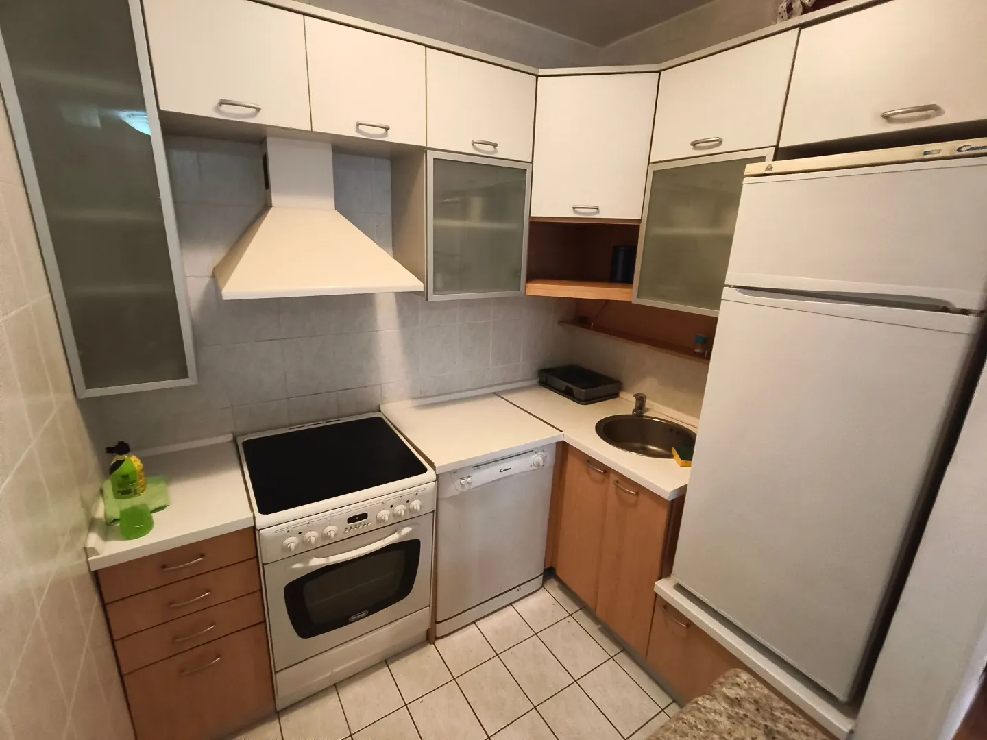 Small equipped kitchen with white cabinets and a refrigerator.
