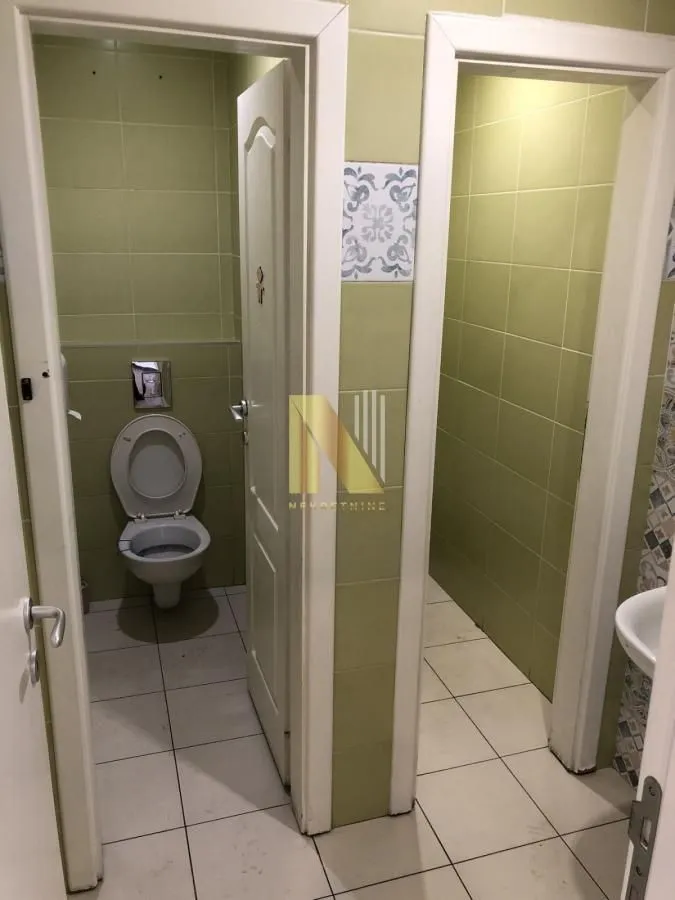 View of the bathroom with sanitary fixtures and green tiles.
