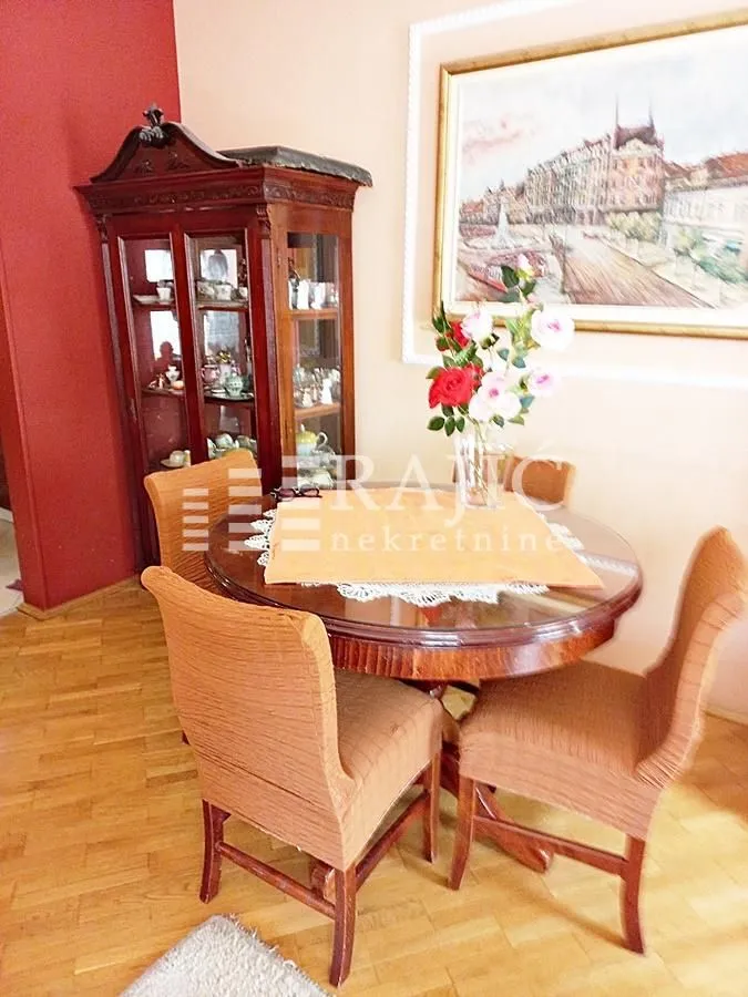 Dining area with a wooden table, chairs, and a display cabinet.