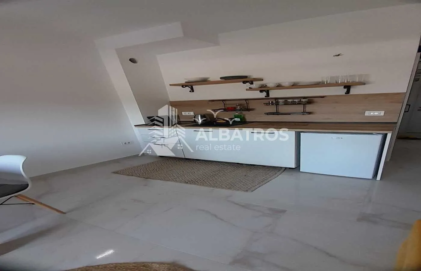 Small kitchen with open shelving and white units.