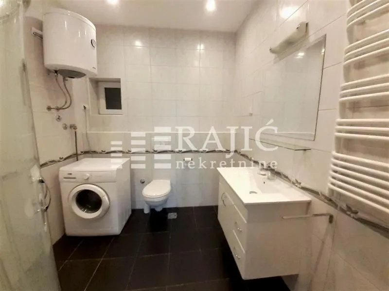 Fully equipped bathroom with a washbasin, washing machine, and toilet.