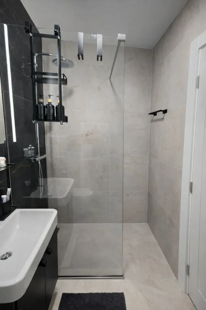 Modern bathroom with a walk-in shower, glass partition, and a washbasin.