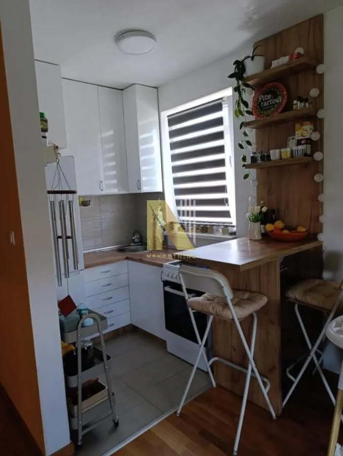 Small equipped kitchen with white cabinets and a dining bar.