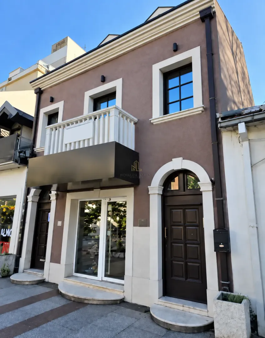 Facade and entrance of a commercial and residential building with a balcony.