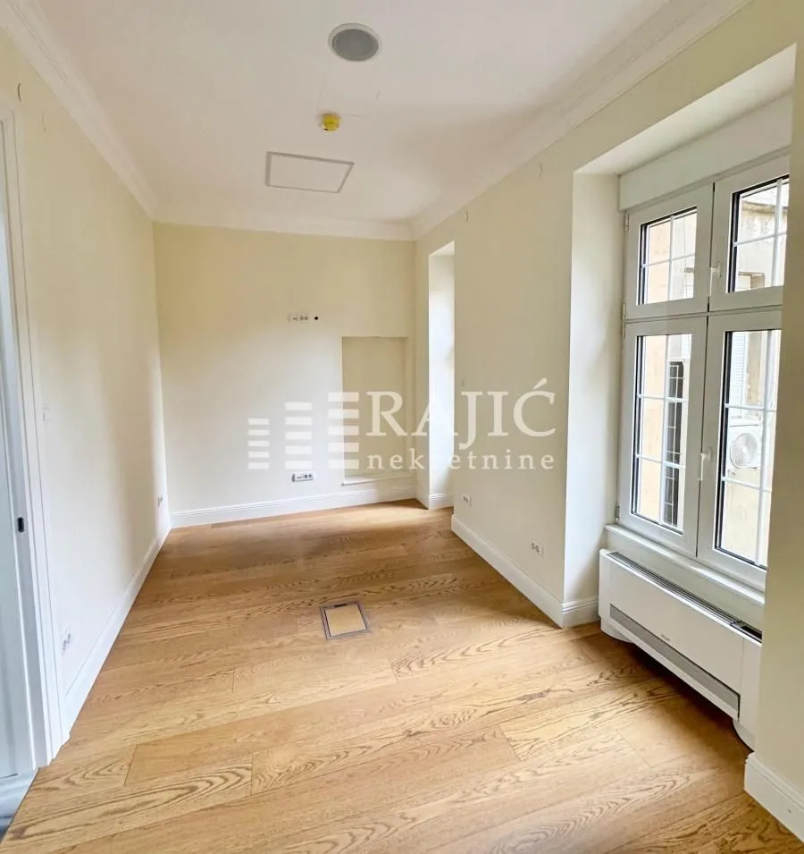 Empty room with wooden flooring and a window.