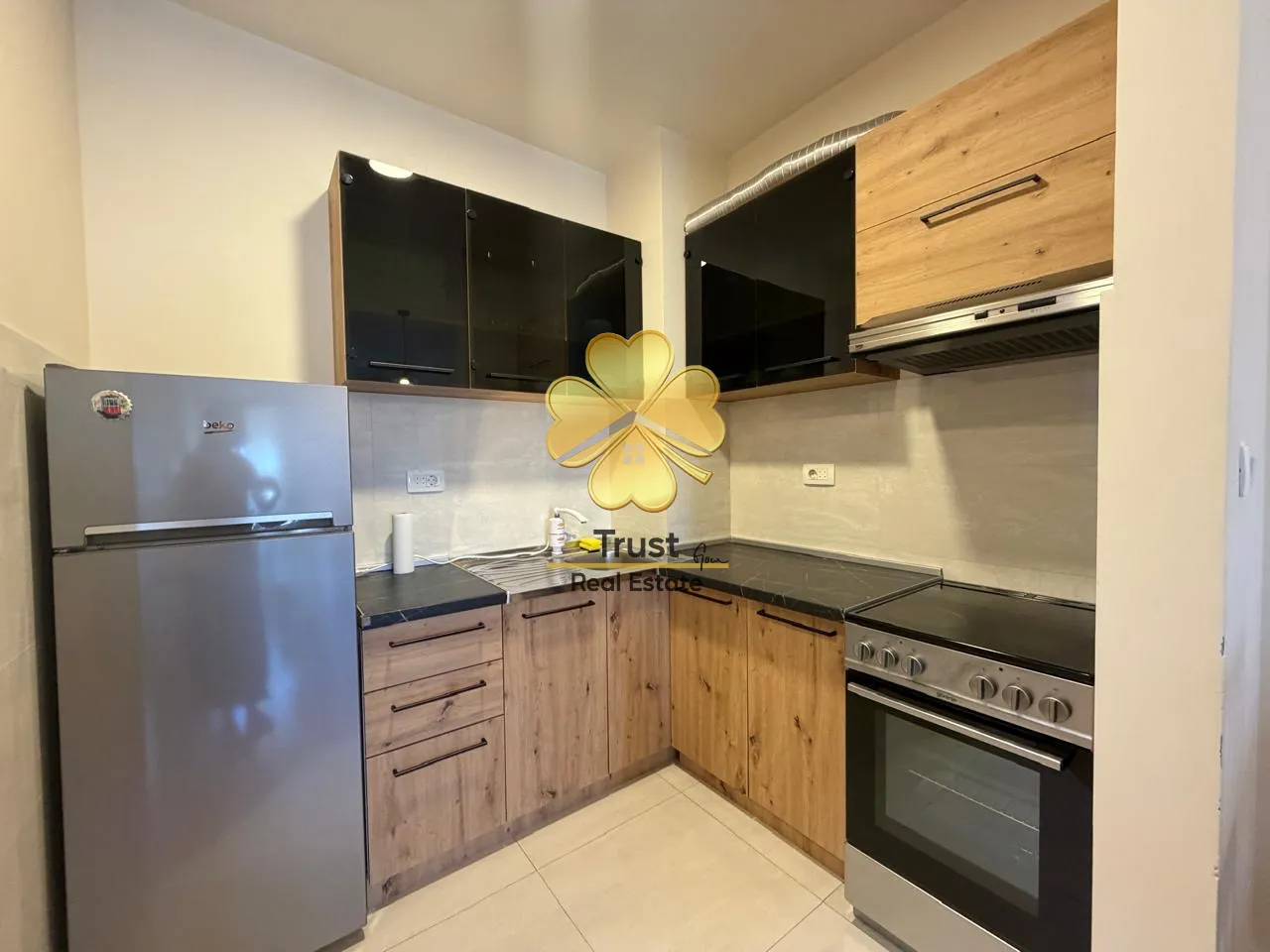 Small kitchen with wooden elements, refrigerator, and stove.