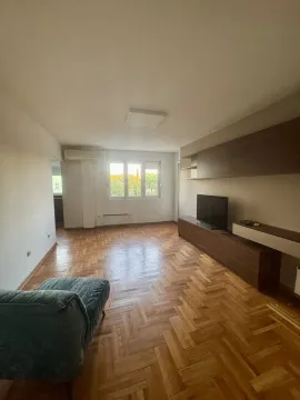 Living room with wooden parquet flooring, furniture, and a television. - image 8