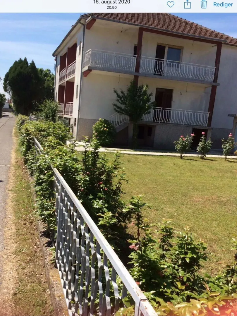 Dvorište i fasada dvospratne kuće sa zelenim travnjakom.