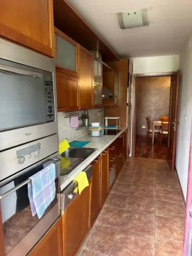 Narrow kitchen with wooden cabinets and built-in appliances. - image 7