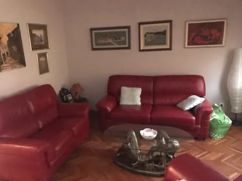 Dnevna soba sa crvenom kožnom garniturom i staklenim klub stolom. - image 3