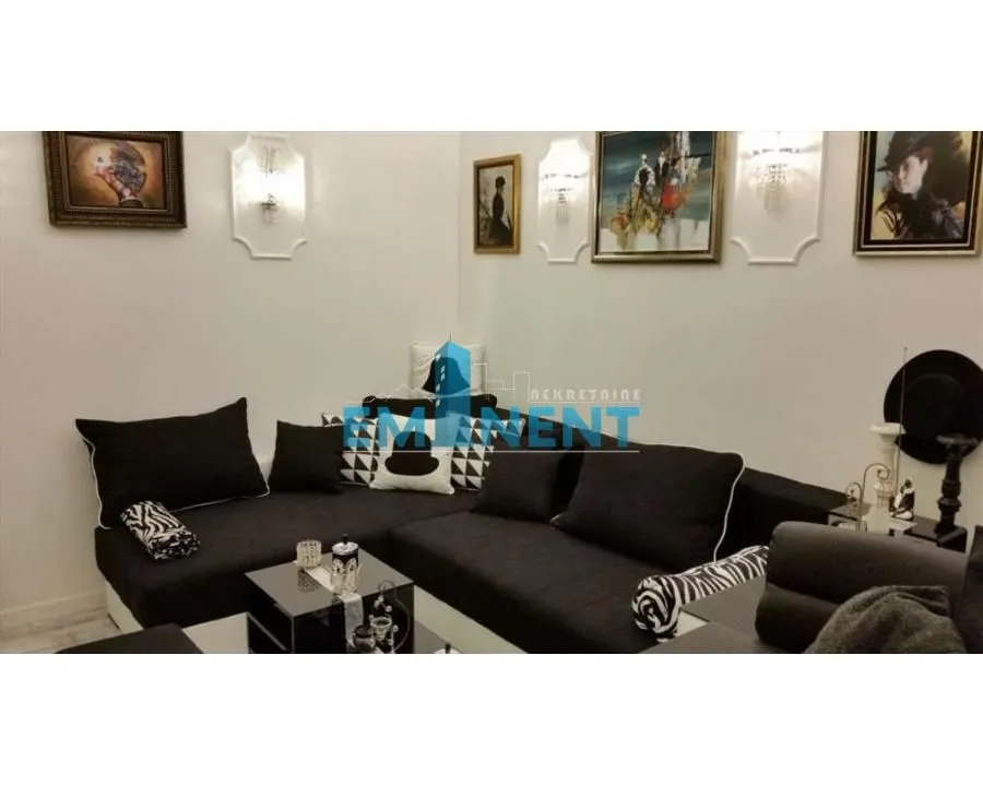 Living room with a black sectional sofa and artwork on the wall.