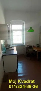 Manja kuhinja sa sudoperom, radnim elementima i trpezarijskim stolom pored prozora. - image 3