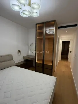 Bedroom with a bed, a large fitted wardrobe with lighting, and a dressing table. - image 16