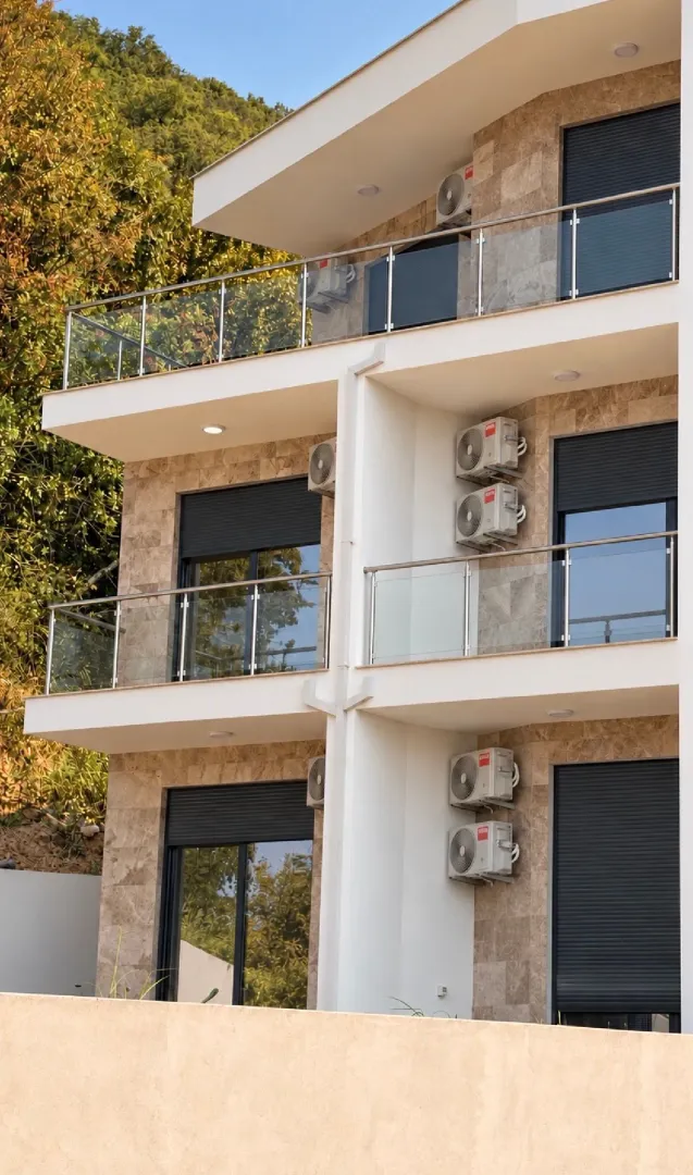 Pogled na spoljašnjost moderne stambene zgrade sa terasam i klima uređajima.