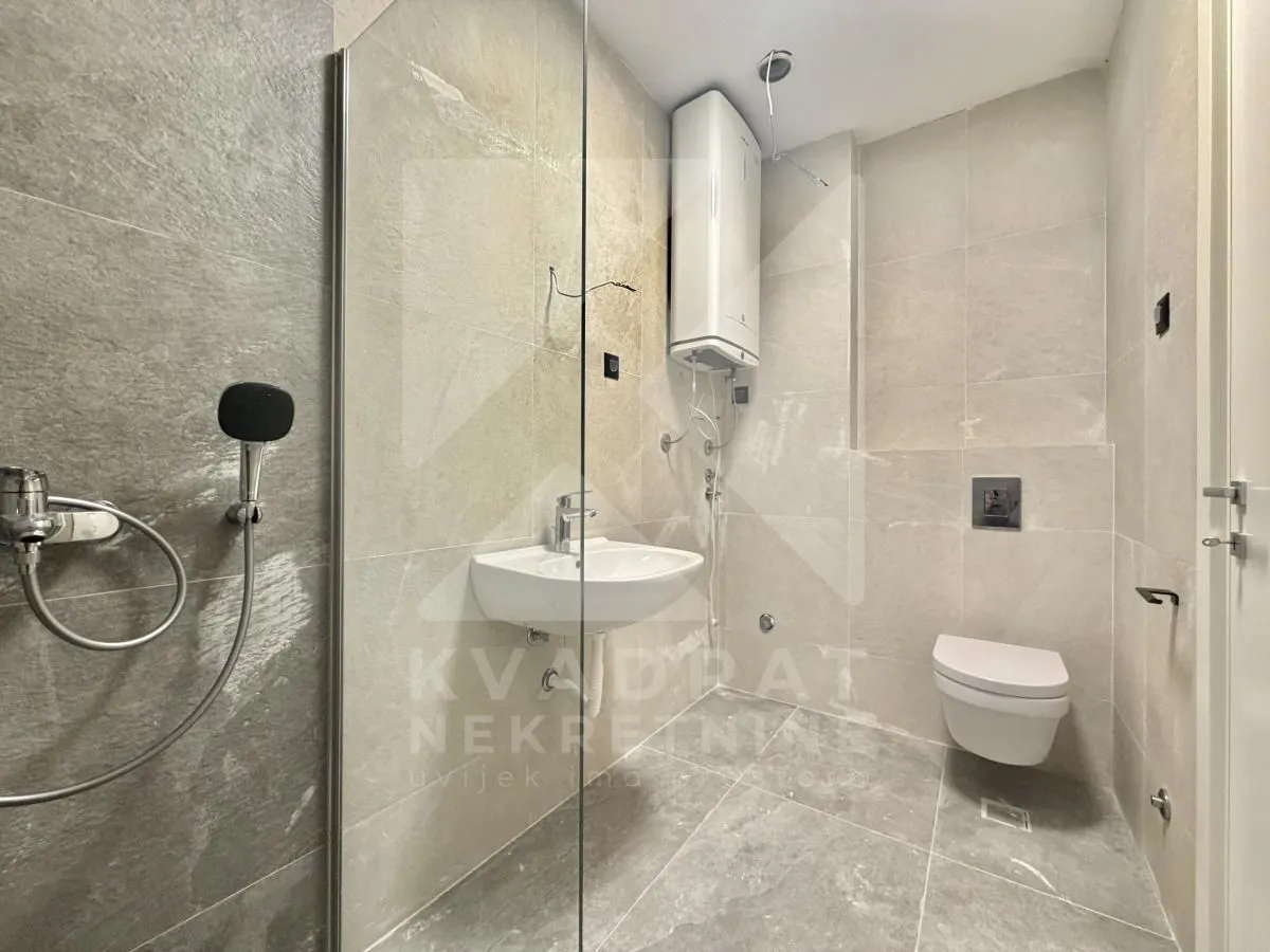 Modern bathroom with a walk-in shower, washbasin, and toilet tiled with ceramic tiles.