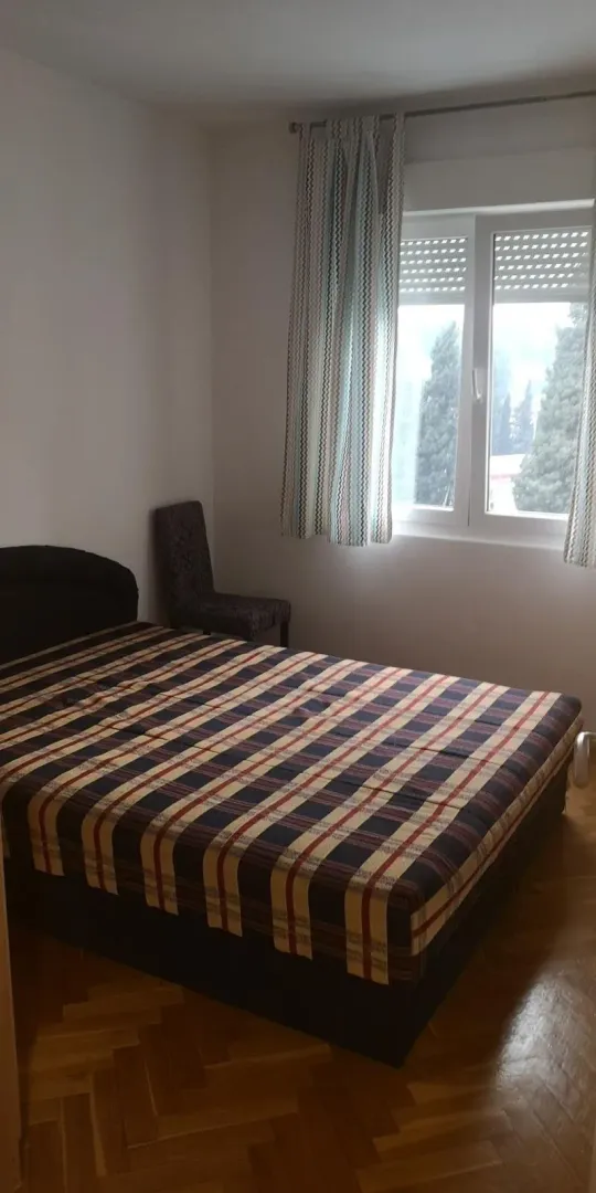Jednostavno namještena spavaća soba sa bračnim krevetom i prozorom.