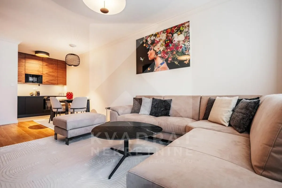 Living room with sofa and view of the kitchen and dining area.