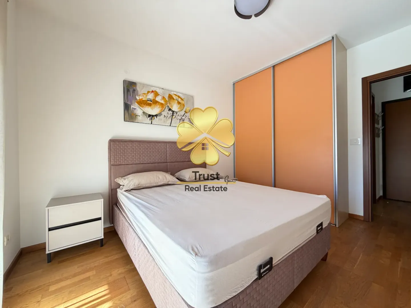 Furnished bedroom with a double bed, a large wardrobe, and a painting on the wall.
