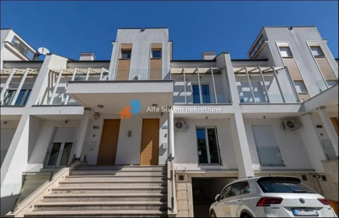 Front view of a modern residential building with an entrance staircase and parking.